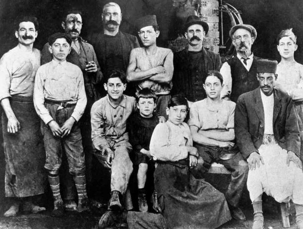 בסדנה של דודו של קאמי (אטיין, קופר) באלג'יר בשנת 1920: אלברט קאמי (בן 7) נמצא באולם עם חליפה שחורה