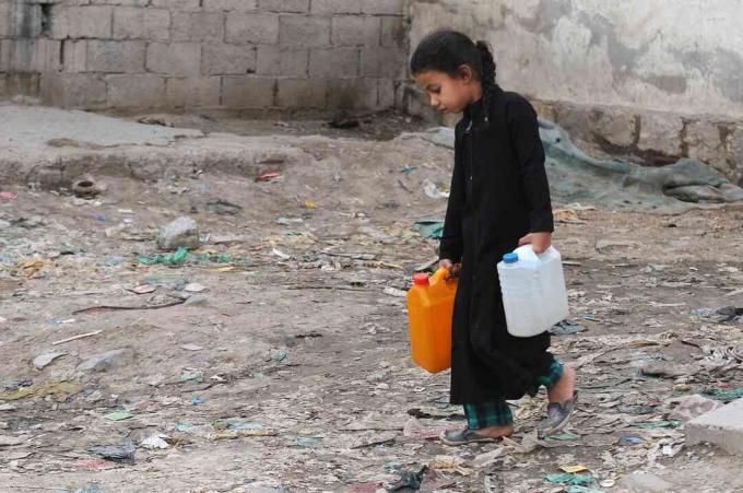 ילדה קטנה סוחבת ג'ריקנים מלאים במים נקיים משאבת צדקה במהלך משבר מים נקיים מתמשך בתימן