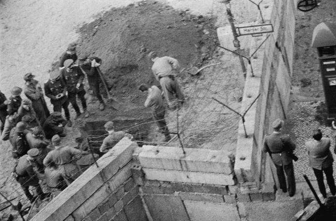 קבוצת חיילים מזרח גרמנים חוקרת מנהרה שנחפרה מתחת לחומת ברלין.