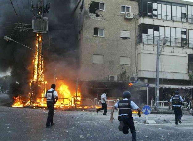 שוטרים ישראלים ממהרים לזירת עמוד בוער חשמל ופגעו בבנייה רגעים לאחר שמטח של רקטות חיזבאללה פגע ב -13 ביולי, 2006 בעיירה נהריה שבצפון הארץ.