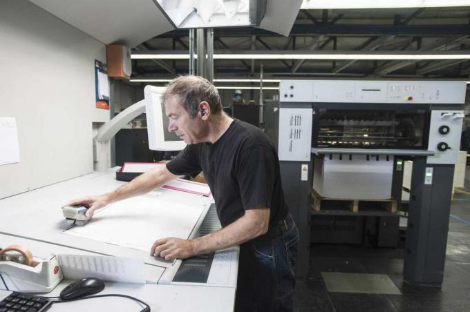 עובד מכין ציוד דפוס דיגיטלי בסדנת הדפוס