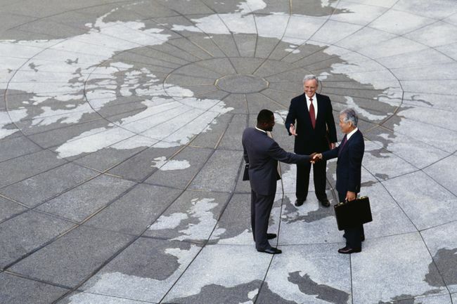  אזוריות כלכלית: אנשי עסקים לוחצים ידיים על מפת הגלובוס.