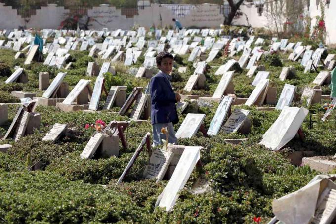 ילד מסתובב בין קברי אנשים שנהרגו במלחמה המתמשכת בבית קברות בצנעא, תימן.