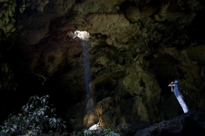 תייר מצטלם בכניסה למערת קלצ'טוק באוקסקינטוק, מדינת יוקטן בחצי האי יוקטן במקסיקו.